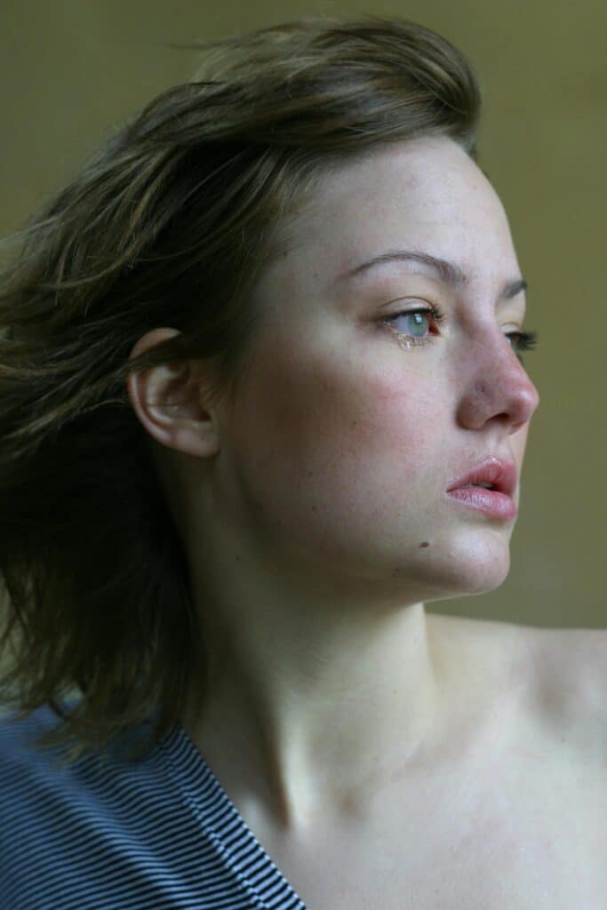 A young woman looks thoughtfully into the distance, capturing emotions with a side profile view.